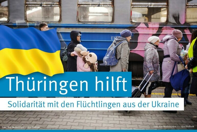 Menschen in Winterkleidung und mit Reisekoffern vor einem Zug